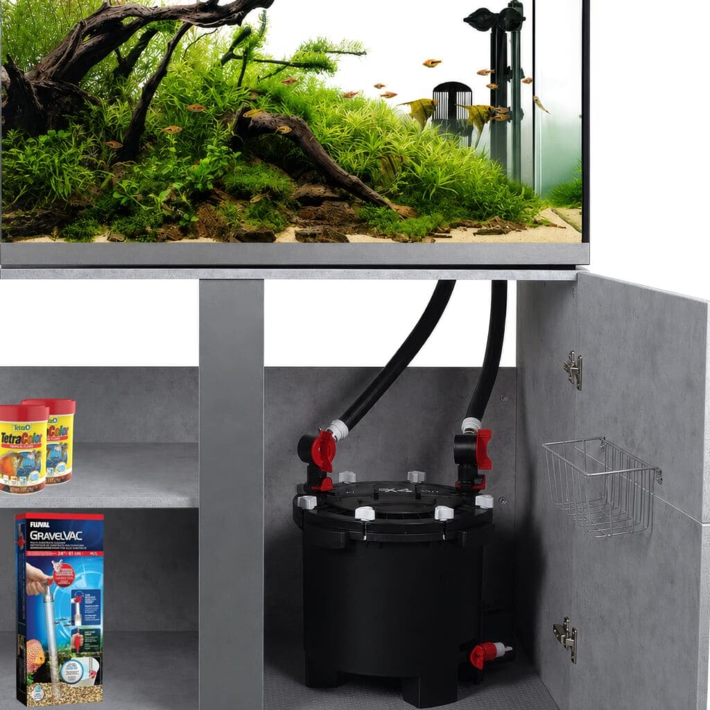A modern aquarium with lush green plants and fish sits on a cabinet. Inside, a Fluval aquarium filter and shelves hold fish food and cleaning supplies, perfect for easy aquarium filter cleaning and preventing cloudy aquarium water.
